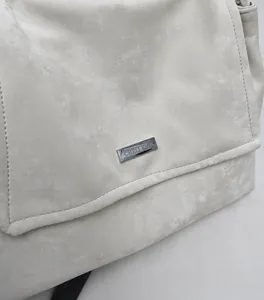 Detail view of cream leather tote bag with silver logo plate and soft texture