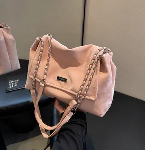 Detailed close-up of pink suede chain bag texture and silver logo plate on the front
