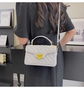 Sac à bandoulière matelassé avec fermoir doré et poignée porté par un mannequin