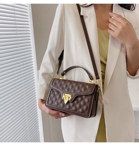 Détail du sac à bandoulière matelassé marron foncé avec fermoir doré et bandoulière cuir