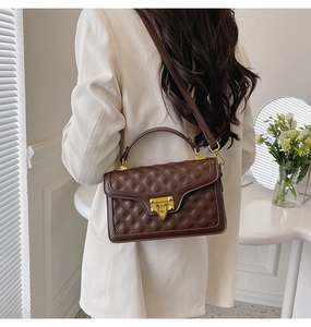 Détail d'un sac bandoulière matelassé marron avec sangle réglable et fermoir en métal doré