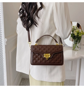 Modèle portant un sac bandoulière matelassé marron foncé avec boucle dorée