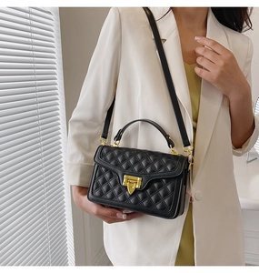 Détail d'un sac à main en cuir matelassé noir avec fermoir métallique doré et poignée