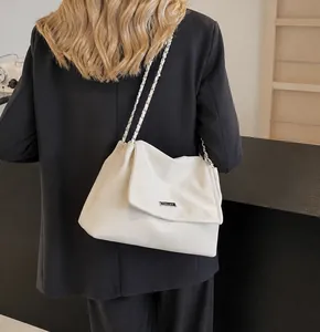 Detail showing the white textured flap bag with a silver chain strap on a grey suit