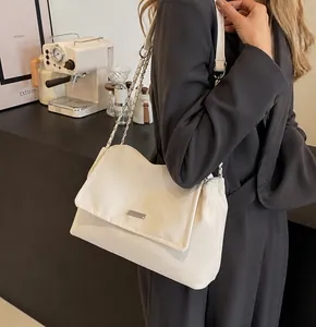 Detail of white leather shoulder bag with silver chain strap and minimalist metal buckle