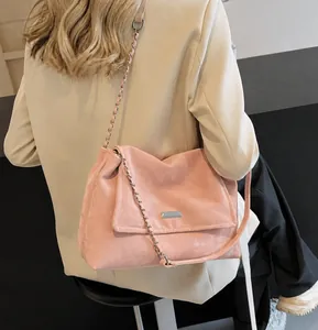 Detail of pink suede shoulder bag with gold chain strap on model in suit