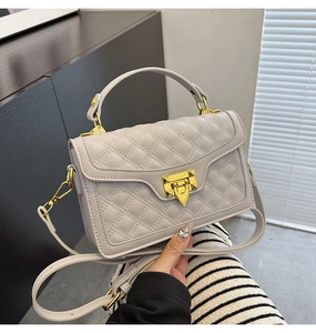 Détail d'un sac matelassé gris avec fermoir doré et poignée supérieure élégante
