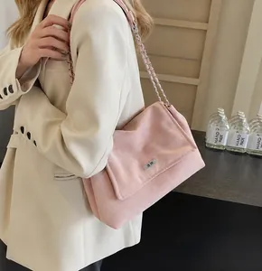 Detail of light pink crossbody bag with silver chain strap and velvet texture on model