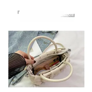Top view of cream ruched cloud handbag showing spacious interior for phone and makeup