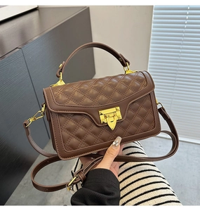 Détail d'un sac bandoulière matelassé marron avec fermoir doré et rivets élégants
