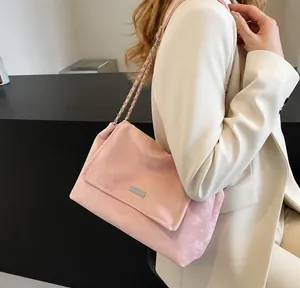 Detail of dusty rose suede shoulder bag with metallic nameplate and chain strap
