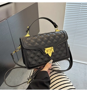 Détail d'un sac à main noir matelassé avec fermoir doré et texture de la poignée