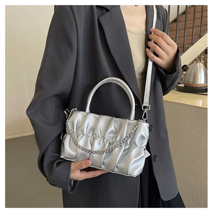 Close-up of silver pleated crossbody bag with metallic finish and metal chain detail