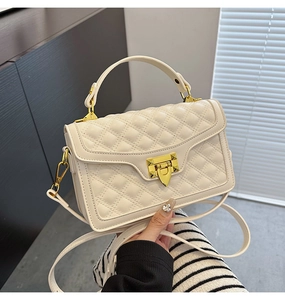Détail du sac matelassé crème avec fermoir doré et poignée élégante de luxe