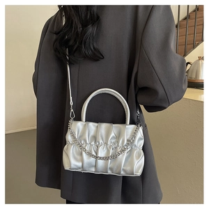Silver pleated cloud handbag with chunky chain detail shown on shoulder of a model