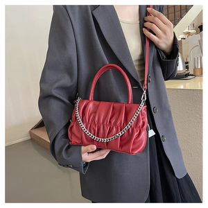 Detail of red pleated handbag with silver chain and adjustable leather strap