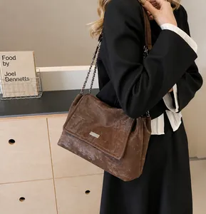 Detail of vintage brown tote bag with chain strap and matte texture on tweed blazer
