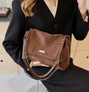 Detail of dark brown leather tote with vintage texture and stylish metal chain strap