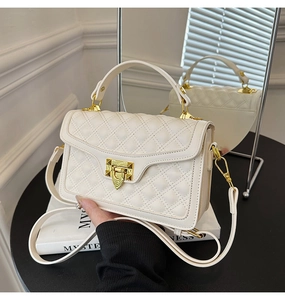 Détail du sac à bandoulière matelassé blanc avec fermoir doré et bandoulière en cuir au miroir