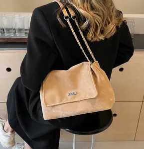 Detail of light brown suede shoulder bag with silver logo plate and chain strap detail