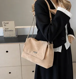 Detail of light tan crossbody bag with matte retro texture and metal chain strap on model