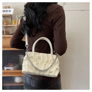 Detail view of cream pleated crossbody bag with chunky silver chain and leather strap