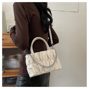 Detail of white ruched crossbody bag with silver chain and pleated PU leather texture