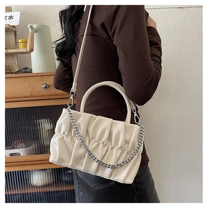 Detail of cream pleated crossbody bag featuring silver chain and textured handle