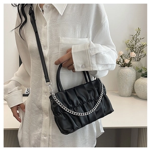 Detail of a black pleated crossbody bag with silver chain and adjustable shoulder strap