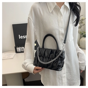 Detail of black pleated cloud bag with silver chain strap and leather crossbody handle