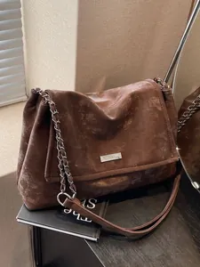Retro brown large capacity tote bag with vintage texture and chain strap on black cabinet