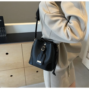 Detail of black lychee-pattern bucket bag with gold clasp and adjustable strap