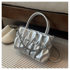 Detailed view of silver pleated texture and metallic chain on modern handbag