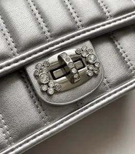 Dettaglio borsa trapuntata argento con fibbia ovale in metallo e cristalli luminosi