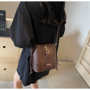 Detail of dark brown bucket bag with lychee texture and adjustable shoulder strap