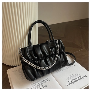 Close-up of black gathered leather handbag with polished silver metal chain strap