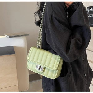 Detail of light green quilted crossbody bag featuring silver chain strap and metal lock