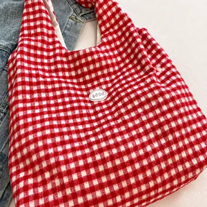Detail of red and white checkered knit tote bag with embroidered good badge ornament