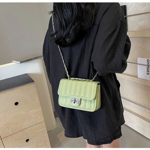 Close-up of light green quilted crossbody bag with silver twist lock and chain strap