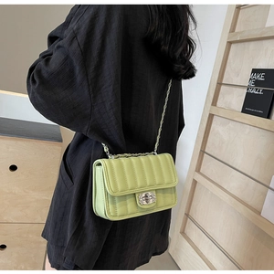 Detail of light green quilted crossbody bag with silver chain and diamond buckle on model