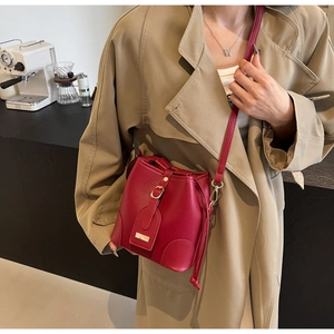 Detail of red leather bucket bag with pebble texture and gold buckles in a cafe setting