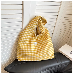 Detail of yellow gingham tote bag featuring an adjustable knotted strap and good logo