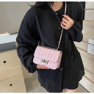 Detail of light pink quilted leather crossbody bag with chain strap and metal lock