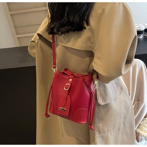 Close-up of red lychee pattern bucket bag with drawstring and metal buckle on trench coat