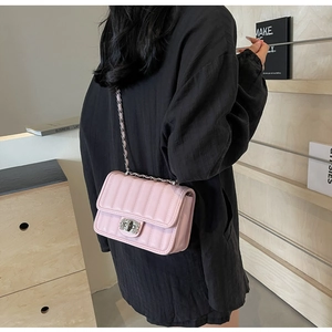 Rear view of a pink quilted chain bag worn by a model in a minimalist wooden room decor