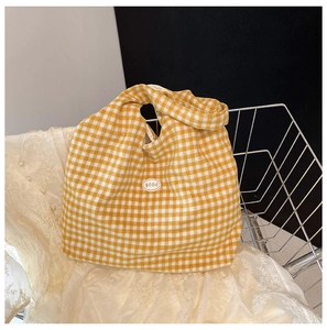 Close-up of yellow and white checkered cotton tote bag with a good label in a metal basket