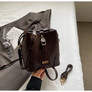 Detail of dark brown lychee textured bucket bag with gold hardware and drawstring