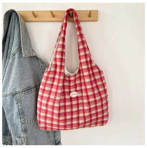 Detail of red and white checkered tote bag with circular good patch hanging on wooden hook