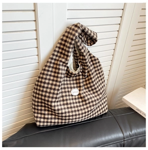 Detail of a large black and yellow checkered knit tote bag with a good emblem