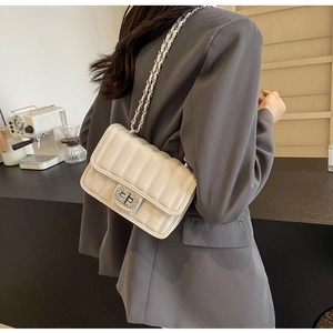 Detail of beige quilted chain bag featuring a diamond pattern and diamond-encrusted twist lock